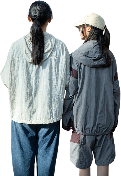 Two people wearing jackets and casual attire stand side by side outdoors with their backs to the camera. Two people wearing jackets and casual attire stand side by side outdoors with their backs to the camera.